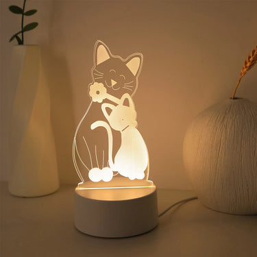 The KittyNook Cat Co. 3D Cat Night Light glows warmly beside two vases, adding calm to the beige surface.